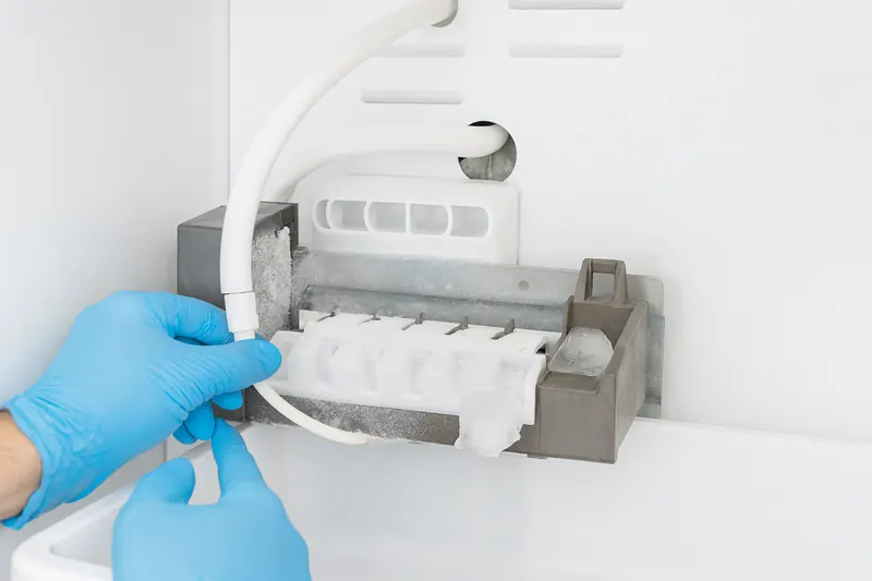 Refrigerator ice maker assembly with a partly filled ice mold and ice built up around the fill area